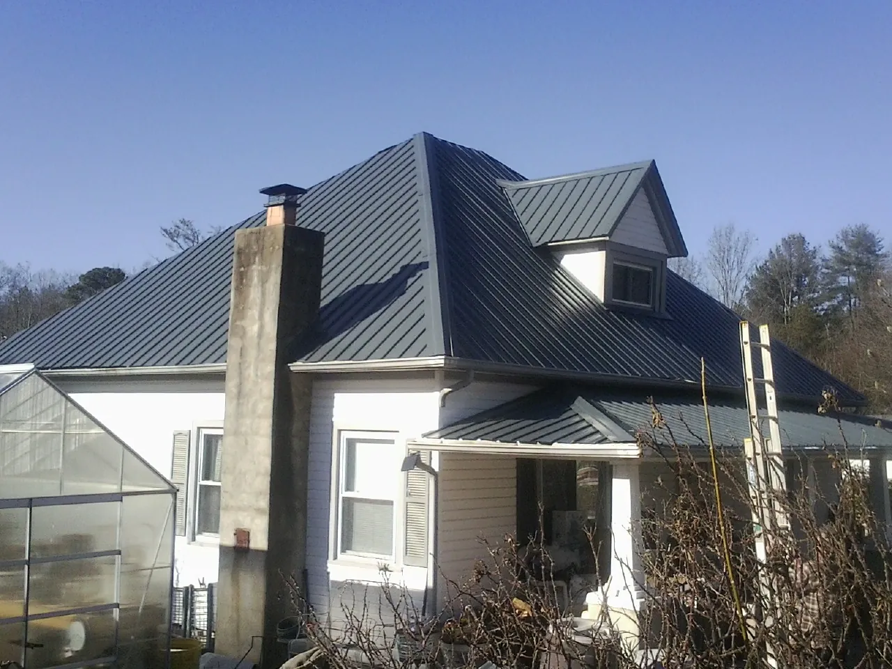 Dark blue standing seam metal roof on a white farmhouse with dormer — Slate & Tile Roof Repair by Roofing Brothers in Fort Covington