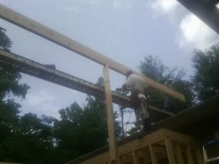 Carpenter setting a ridge beam over a new addition frame — Ice Dam Removal by Roofing Brothers in Fort Covington