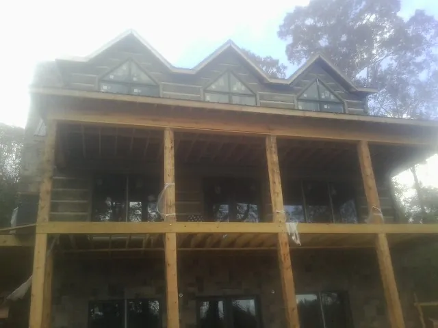 Dormers and porch framing on a large log home under construction — Roof Coating work by our crew in Fort Covington