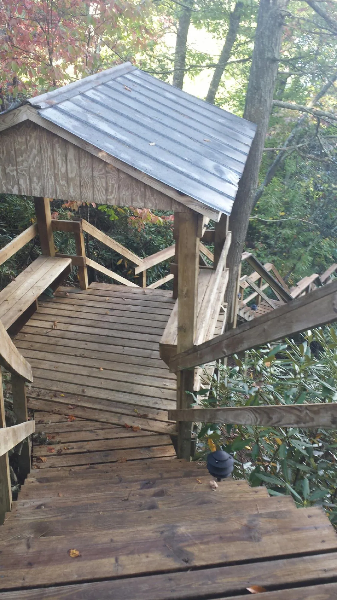 Metal roofed shelter over wooden steps on a wooded walkway — Skylight Repair & Installation work by our crew in Fort Covington