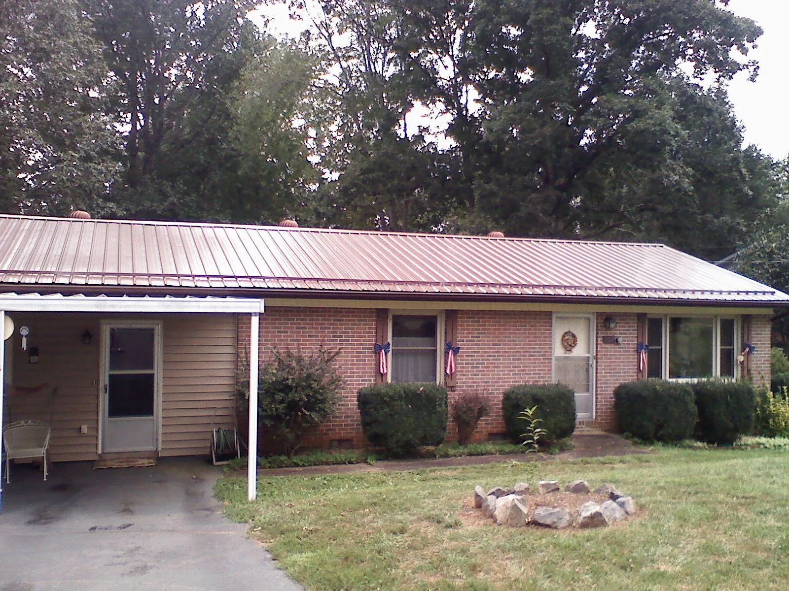 Bronze metal roof and carport on a brick ranch home — Roof Repair work by our crew in Fort Covington