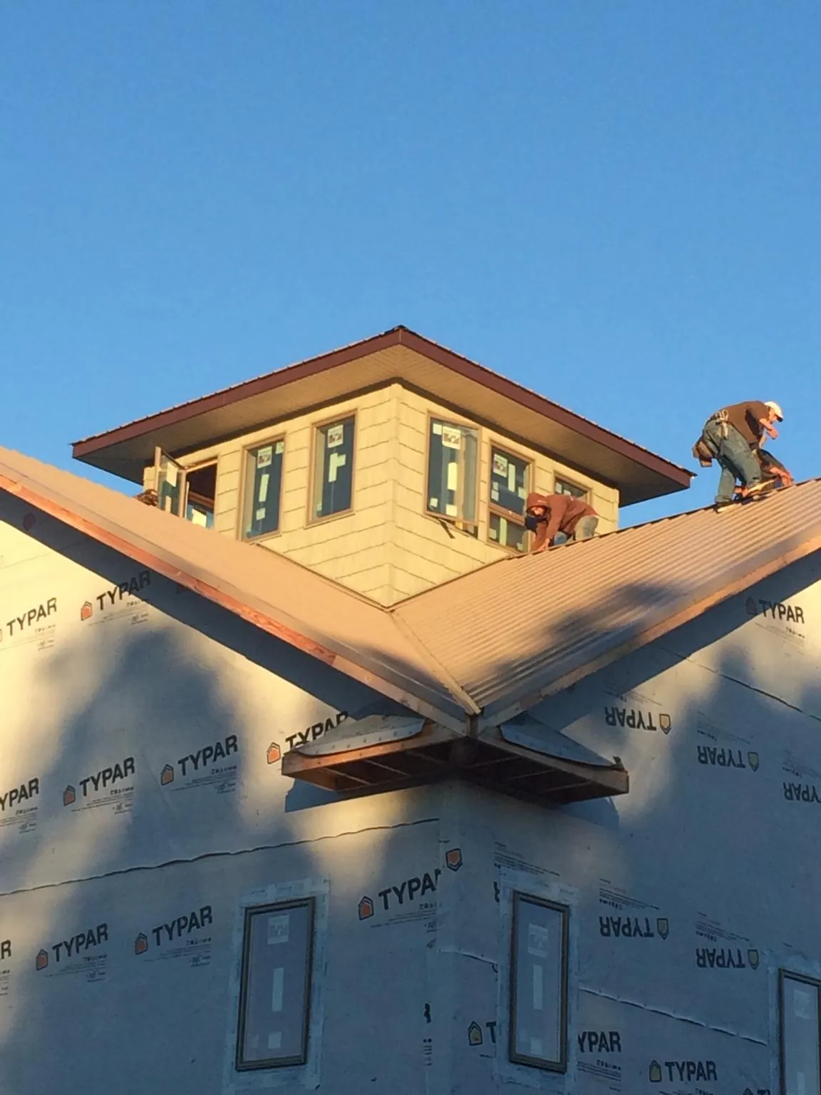 Roofers working around a rooftop cupola on a new metal roof at sunset — Roof Waterproofing in Fort Covington by Roofing Brothers
